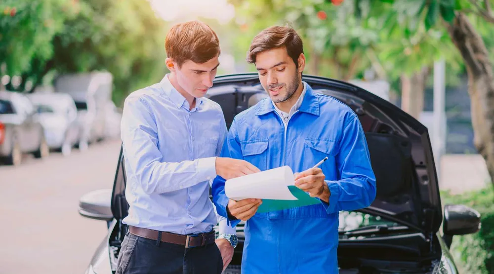Agent reviewing coverage options with a customer beside their car